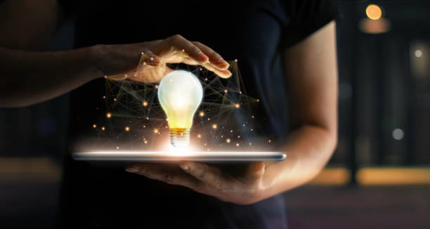 istock Innovation concept. Hands holding tablet and illuminated light bulb with global network connection on screen, Technology and communication on dark background. 1051594036