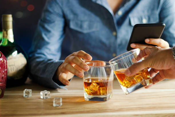 zbliżenie dwóch mężczyzn klin szklanki whisky pić napój alkoholowy razem, podczas gdy w barze w pubie - clink zdjęcia i obrazy z banku zdjęć