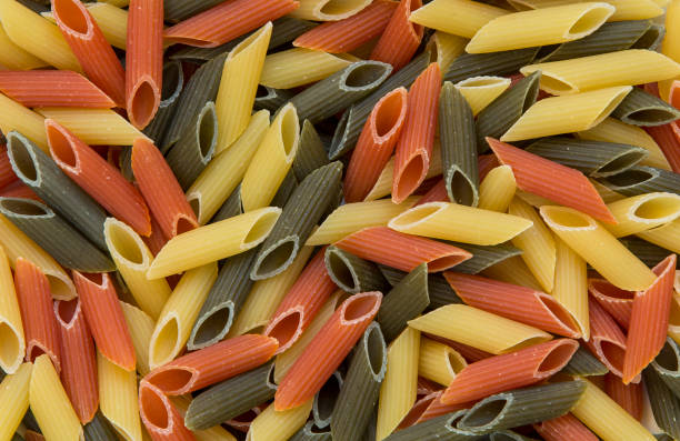 Tri-color penne pasta. Tomato, spinach and wheat pastas. Top view. Tri-color penne pasta. Tomato, spinach and wheat pastas. Top view. carbohydrate food type photos stock pictures, royalty-free photos & images