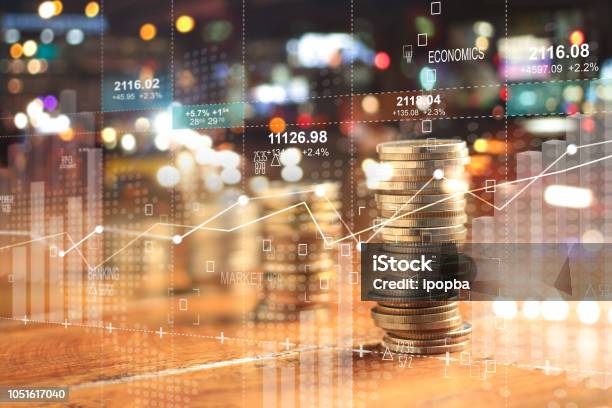 Double Explosure With Businesss Charts Of Graph And Rows Of Coins For Finance At Night City Background Stock Photo - Download Image Now