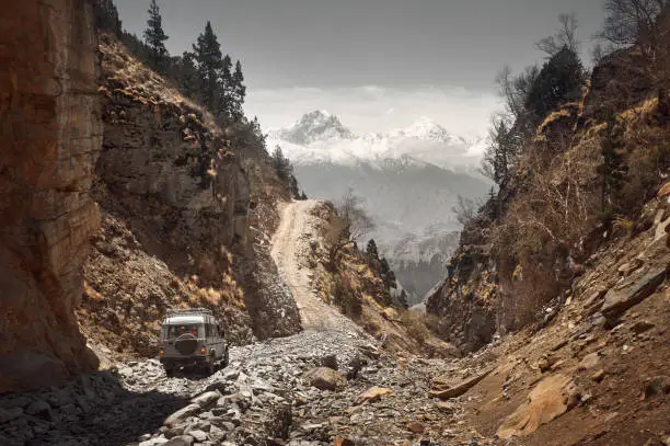 Photo of Off-road vehicle goes an extreme mountain path during an expedition to Himalayas