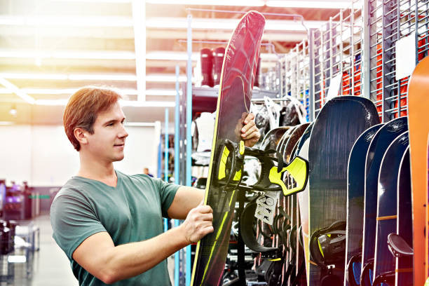 Man chooses snowboard in sport store