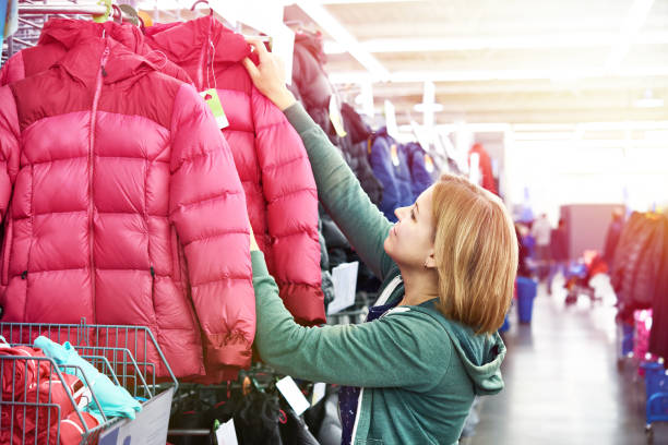 Woman chooses a winter jacket in the store