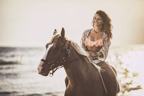 istock Young woman enjoying while riding her horse n the beach. 1051648328