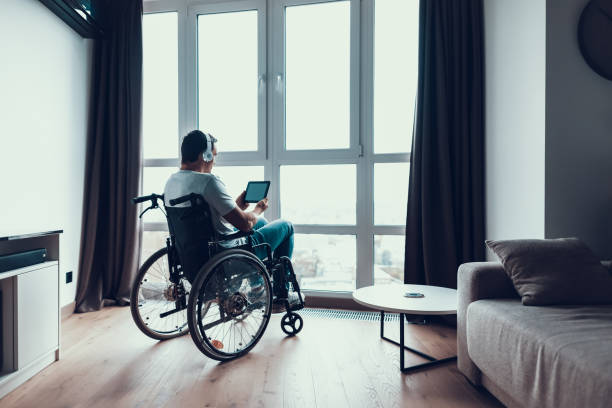 istock Back View Disabled Man Uses Headphones and Tablet 1051655750