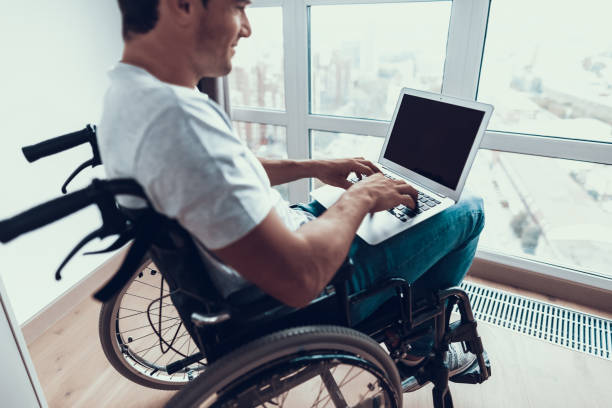 istock Disabled Man Holding Laptop and Typing on Lap 1051655880
