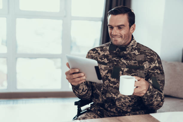 istock Military in Wheelchair Uses Tablet and Drinks Tea 1051655918