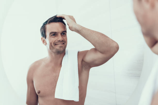 istock Happy Man in Bathroom Looks at Mirror Reflection 1051656190