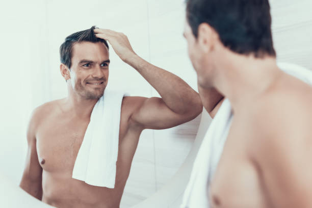 istock Happy Man in Bathroom Looks at Mirror Reflection 1051656194