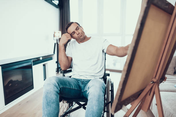 istock Disabled Man Sitting in Wheelchair Opposite Easel 1051656286