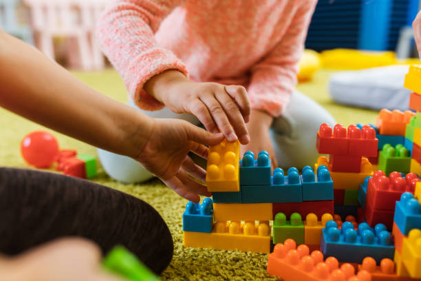 istock Close up of unrecognizable kids playing with toy blocks on carpet. 1051663064