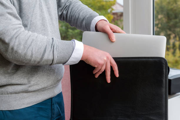 Young business man pulling out a laptop out of a leather case at the office