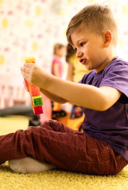 istock Creative little boy playing with toy blocks on carpet at playroom. 1051663408