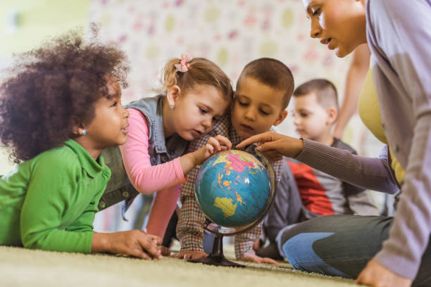 istock Preschool teacher analyzing a globe with small kids in kindergarten. 1051663700