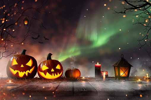 Halloween pumpkins on old wooden planks with spooky background.