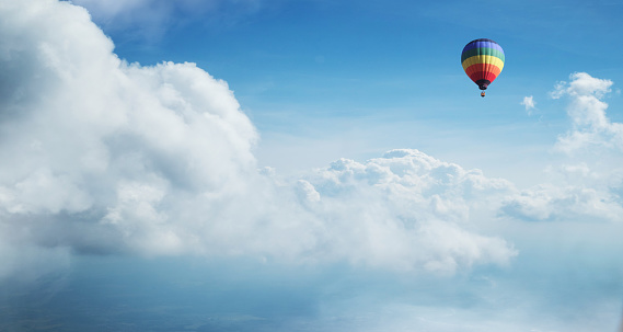 Colorful hot air balloon flying against blue cloudy sky. Lots of copy space.
