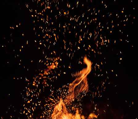 Burning sparks flying. Beautiful flames. Fiery orange glowing flying away particles on black background.