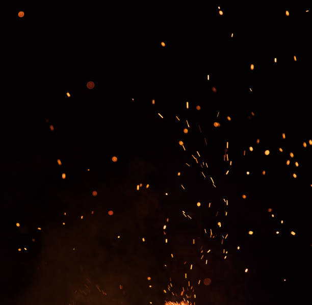 Burning sparks flying. Beautiful flames. Fiery orange glowing flying away particles on black background.