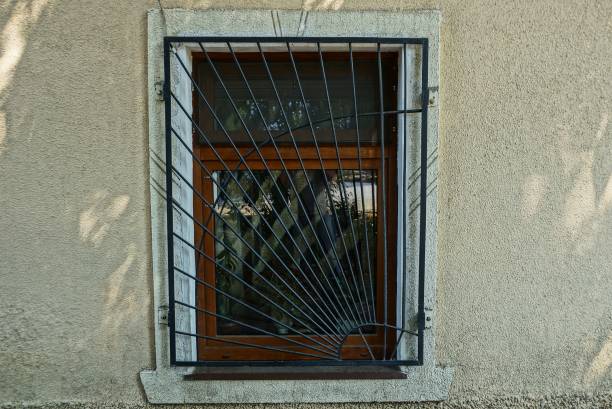 istock one old brown window behind bars on a gray concrete wall of a building 1051670162