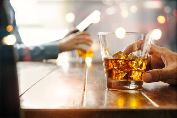 Close-up of two men clinking whiskey drink alcoholic beverage at bar counter in the pub background. Close-up of two men clinking whiskey drink alcoholic beverage at bar counter in the pub background. friends in bar with phones stock pictures, royalty-free photos & images