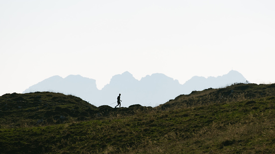 Silhouette of a man who practices Nordic walking in the mountains