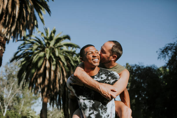 pareja gay abrazando en el parque - gay man homosexual men kissing fotografías e imágenes de stock