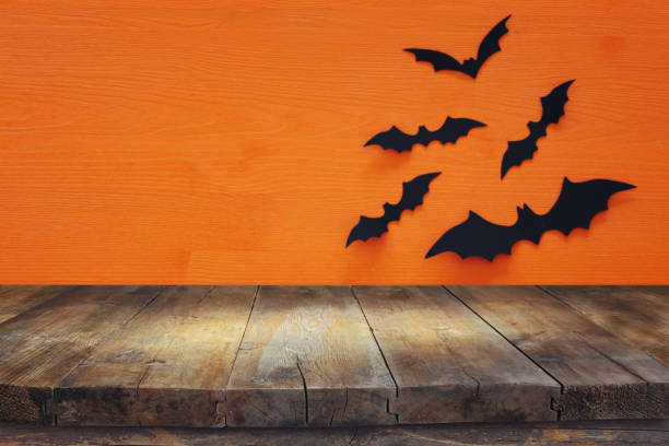 istock Halloween holiday concept. Empty rustic table in front of black bats background. Ready for product display montage. 1051674260