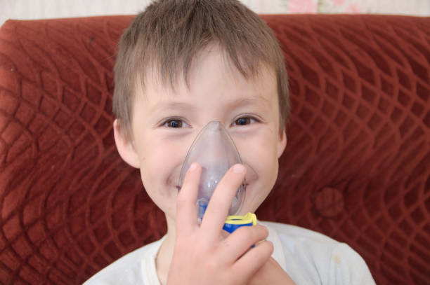 istock smiling sick boy in nebulizer mask making inhalation, respiratory procedure by pneumonia or cough for child,  inhaler, compressor nebulizer,  nebules machine for health care. Kid catch cold 1051675008