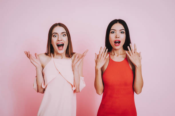 istock Two Surprised Girls in Dresses on Pink Background 1051678428