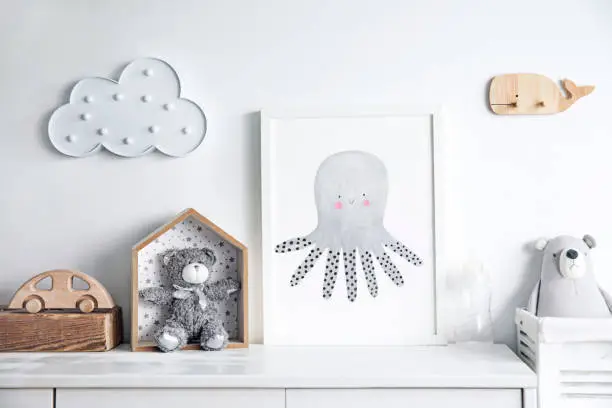 Stylish scandinavian nursery interior with mock up photo frame.