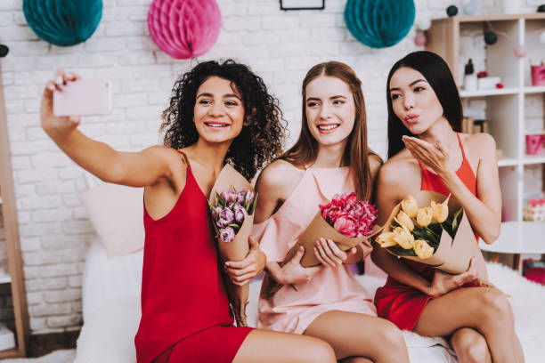 istock Beautiful Girlfriends with Flowers Making Selfie. 1051678468