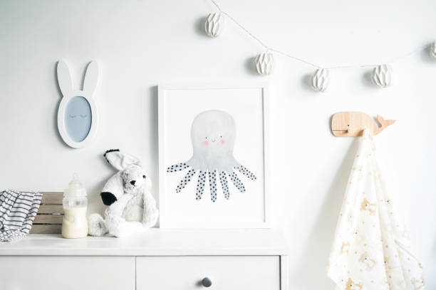 istock Stylish nursery shelf with mock up photo frame, plush rabbit, box for accessories. White background wall with cotton lamps.. 1051678604