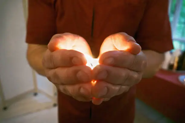 Burning candle in masseur hands. Closeup horizontal shot