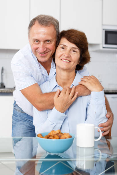 istock Happy mature couple hugging near kitchen table before drinking tea 1051695724
