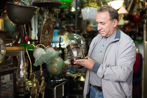 Middle aged man buying retro handicrafts on indoor flea market