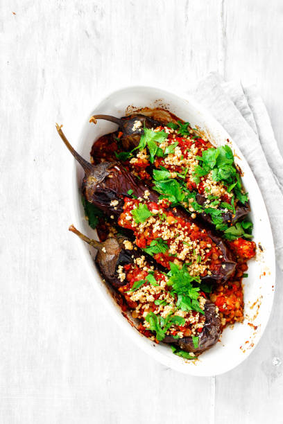 Stuffed eggplant lentils tomatoes nuts wooden table top view