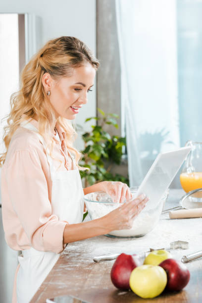 istock attractive young woman making dough and using tablet at home 1051706484