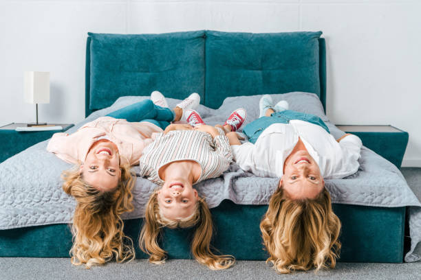 istock smiling three generations of women lying on bed and looking at camera 1051709908