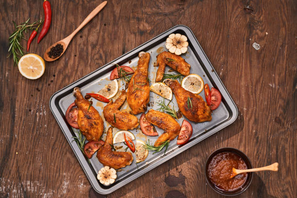 istock Grilled chicken drumstick and wings on baking tray over wooden table 1051712408