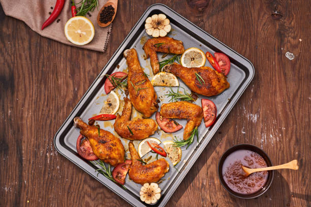 istock Grilled chicken drumstick and wings on baking tray over wooden table 1051712464