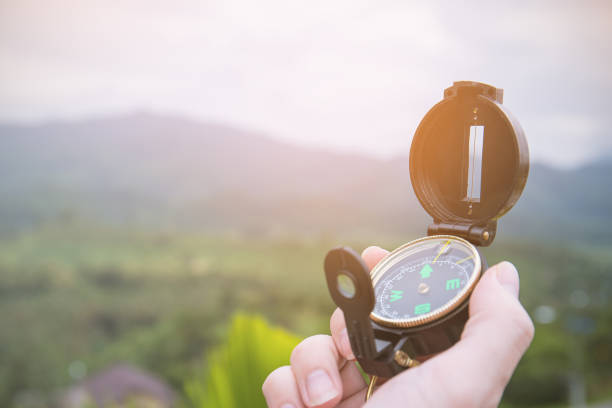 Hand holding compass Hand holding compass at mountain over sunset sky almaty photos stock pictures, royalty-free photos & images
