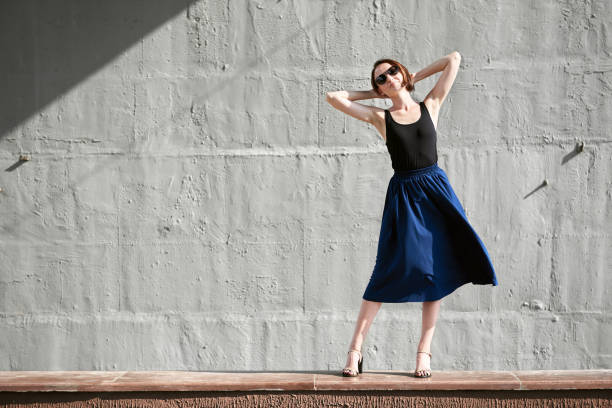 istock young girl posing against a concrete wall, dressed in black, hard light and shadows 1051721140