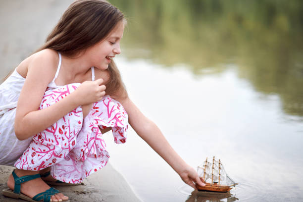 istock girl playing with a toy sailing ship by the river 1051721460