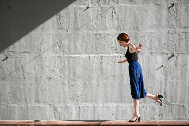 istock young girl posing against a concrete wall, dressed in black, hard light and shadows 1051723798