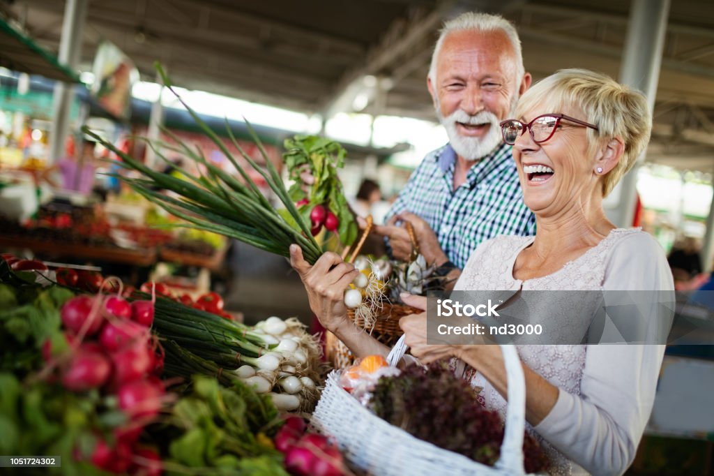 市場で野菜のバスケットを持って笑顔のシニア カップル - シニア世代のロイヤリティフリーストックフォト