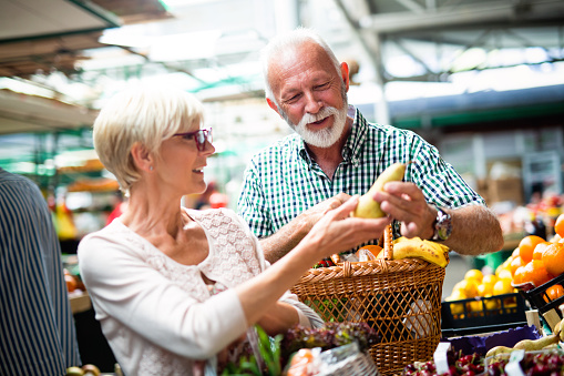 Senior pareja familia elegir bio alimentos frutas y verduras en el mercado durante compras semanales photo