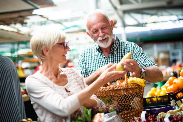 Senior couple choosing bio food fruit and vegetable on the market during weekly shopping
