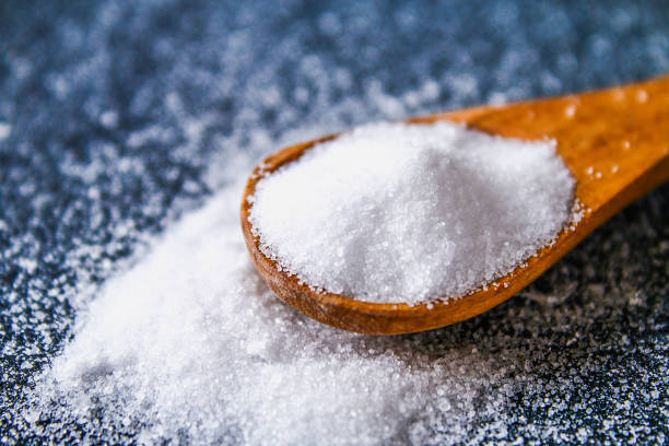 crystals of shallow salt in a scoop, spoon on a dark gray table. background for advertising salt. table salty. salted food. - saleiro de mesa imagens e fotografias de stock