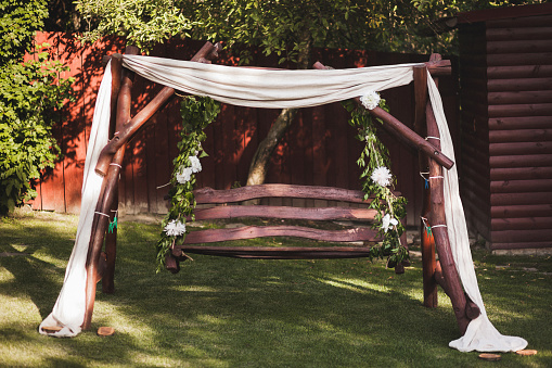 Wooden swing, decorated with flowers and cloth for the wedding