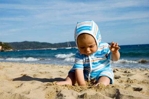 Bambino che gioca con la sabbia in spiaggia - foto stock